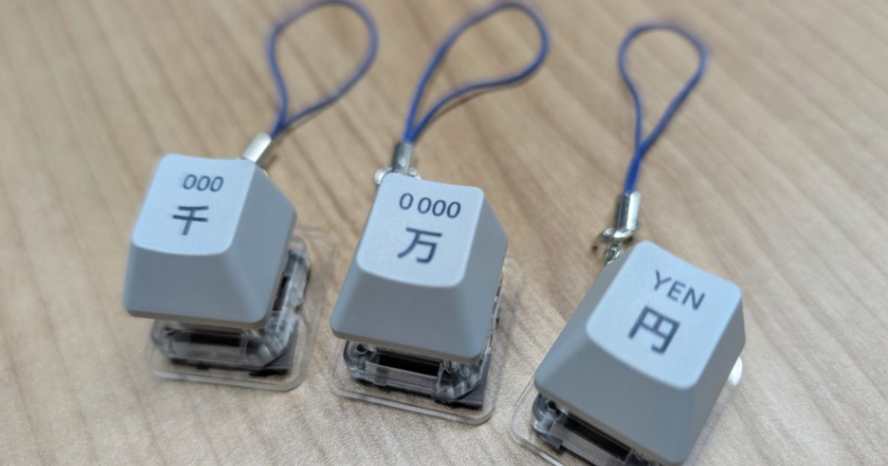 東プレ製「万」「円」「訂正」キーストラップ、セブン銀がプレゼントへ　ATMの打鍵感再現