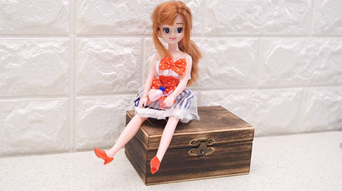 リカちゃん人形が箱の上に座っている
