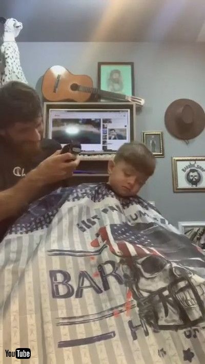 uLittle Boy Falls Asleep While Getting His Hair Cut By Barber - 1200925v