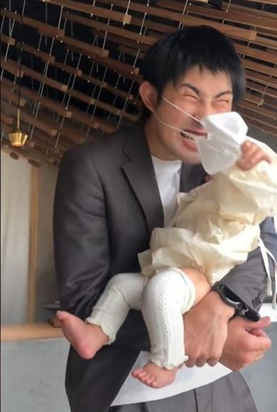 赤ちゃんにマスクを引っ張られるパパ