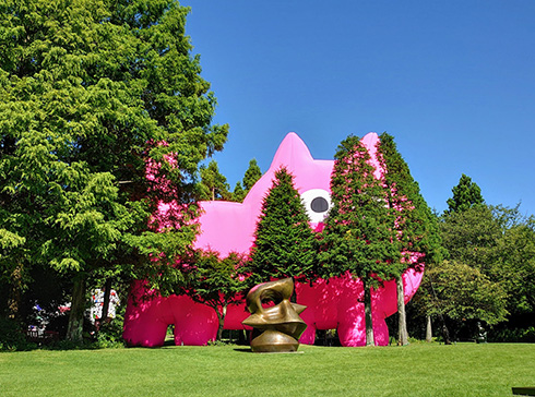 木々のすき間から顔を出す巨大ピンク猫　彫刻の森美術館がデカくてかわいいインスタレーションを展示開始